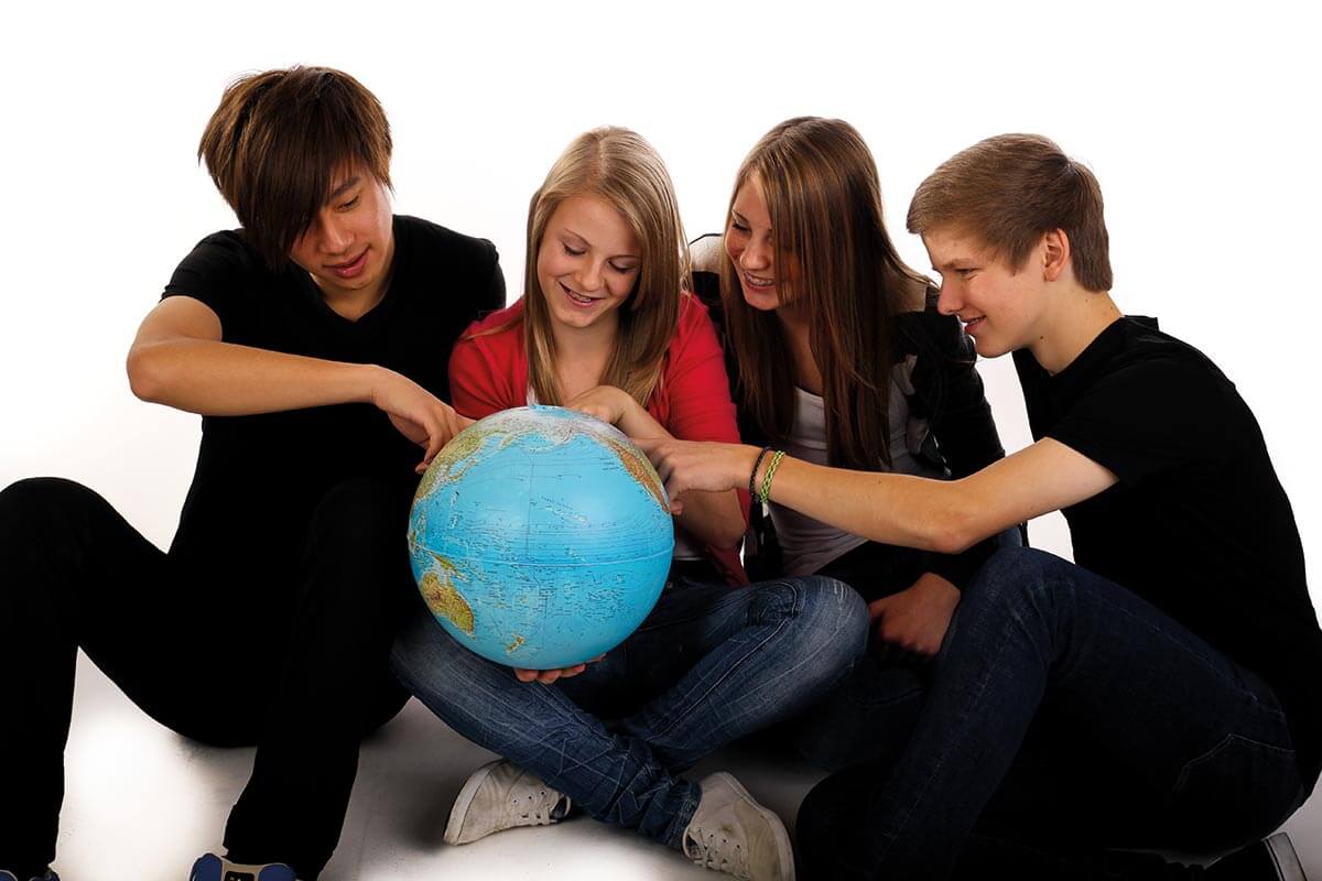 vier Schüler/-innen mit einem Globus
