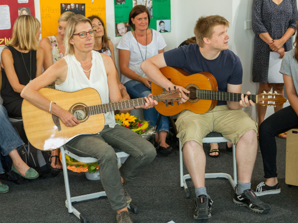 Lehrerin und Schüler spielen gemeinsam Gitarre